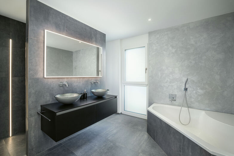 Stylisches Bad mit modernen Badmöbeln und Lichtband in der Dusche.