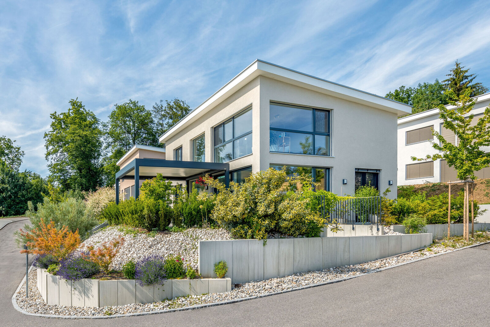 Auf dem Eckgrundstück ist das moderne Einfamilienhaus mit Pultdach optimal an den Hang angepasst.